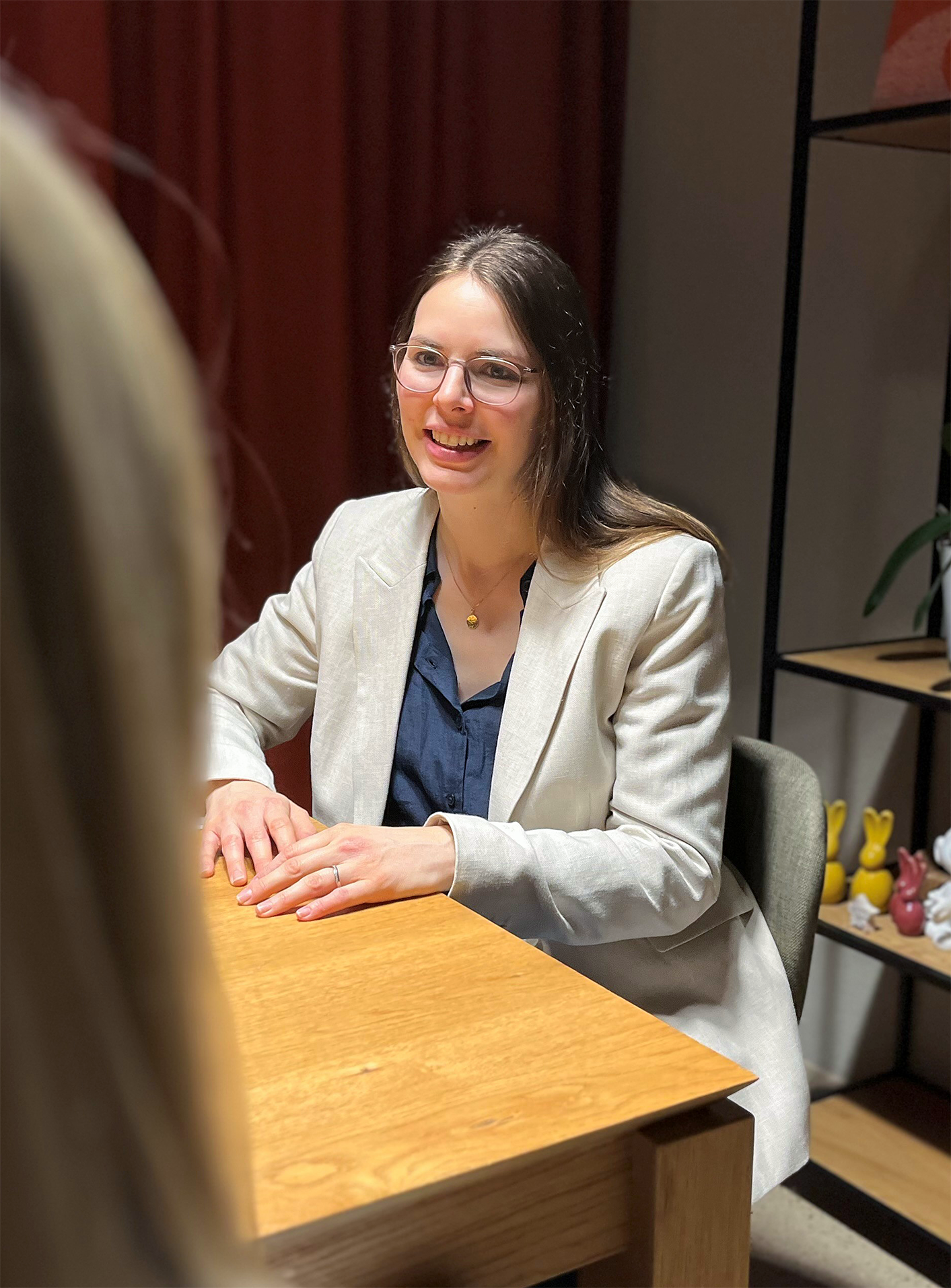 Marktforscherin wird sitzend an eine Tisch interviewt.